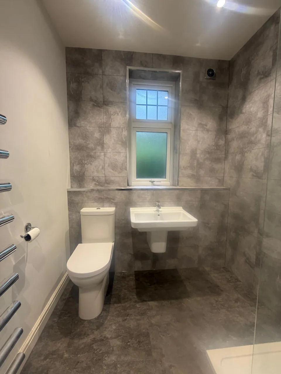 Compact basin and toilet beneath a bathroom window