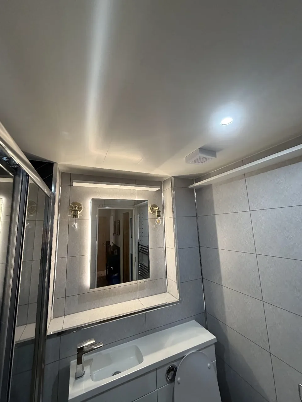 White bathroom furniture and a large illuminated mirror